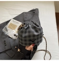 Gros plan du sac seau à carreaux avec bandoulière chaîne et pompon blanc décoratif en détail - Noir avec pendentif