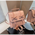 Detailed close-up of a pink checkered backpack with dual bows and stylish leather straps - Pink
