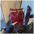 Dettaglio borsa a secchiello bordeaux in pelle con borchie e lunghe frange - Rosso