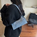 Blue denim shoulder bag with silver studs and curved opening design worn by model - Blue