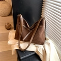 Large dark brown suede tote bag featuring metallic hardware on a white blazer background - Brown