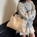 Detail of rivet-studded beige tote bag showing texture and reinforced metal ring strap - Off White