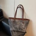 Grey tote bag with brown leather handles and gold logo shown in a studio setting - Black