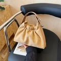 Beige suede dumpling bag with pleated design and silver buckle on a black chair - Khaki