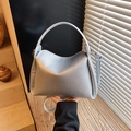 Silver lychee grain leather crossbody bag with top handle in a minimalist setting - Silver