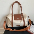 Détail du sac de voyage crème avec bordure en cuir marron et boucle magnétique en métal - Blanc
