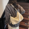 Chic off-white soft leather hobo tote bag shown on model in a cozy indoor setting - White