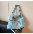Detail of light blue nylon tote bag with front pockets and adjustable strap on a chair - Blue