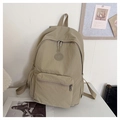 Détail d'un sac à dos en nylon kaki avec texture lisse et logo rond sur bureau blanc - Khaki Foncé