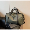 Detail view of large green travel bag with nylon shoulder strap on black leather bench - Green