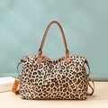 Detailed side view of leopard print travel bag with brown leather handles and strap - Leopard Print