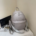 Grey faux leather backpack with woven strap and a small coin purse charm attached - Gray