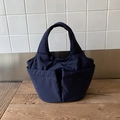 Detail einer dunkelblauen Nylon-Tasche mit mehreren Taschen und dicken Griffen auf Holz - Dunkelblau