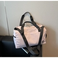 Detail of light pink waterproof travel bag with brand logo on a black sofa - Pink