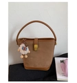 Detail of a brown suede bucket bag featuring a gold twist lock and cute plush lamb charm - Brown