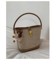 Close-up of beige suede bucket bag with brown leather trim and cute plush bear charm - Apricot