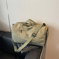 Army green nylon duffel bag with NINGJIA logo and adjustable shoulder strap on sofa - Green