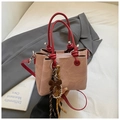Detail of pink bucket bag with red handles, bow charm, and inner zipper pocket - Pink with Pendant