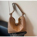 Detail of a brown PU leather tote bag with a knotted strap on an artistic book background - Khaki