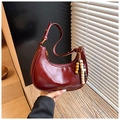 Détail d'un sac demi-lune en cuir rouge foncé avec un pendentif en perles de bois - Rouge avec Pendentif