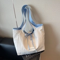 Bolso tote de nailon en azul y beige sobre silla de cuero negro con un libro - Blanco Roto