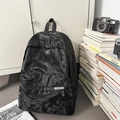 Detail view of camouflage backpack with brand label near books and a retro camera - Black