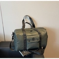 Olive green travel duffel bag with black straps on a black leather sofa - Green