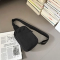 Borsa a tracolla minimalista in nylon nero su una scrivania con libri e riviste d'arte - Nero
