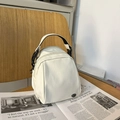 Mini bolso bandolera de nailon crema con asas negras sobre una revista de moda - Blanco Sin Colgante