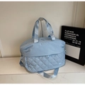 Detail view of light blue travel bag featuring diamond-quilted pattern and nylon handles - Blue
