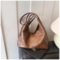 Detailed close-up of a brown leather Hobo bag resting on books in a cozy home setting - Brown