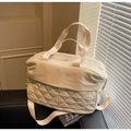 Detail of a beige quilted travel bag featuring reinforced handles and a shoulder strap - Off-white
