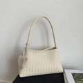 Detail of beige woven bucket bag with smooth texture and triangular charm pendant - White