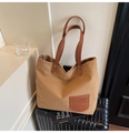 Detailed view of khaki canvas tote bag with dark brown leather handles and small front pocket - Caramel color