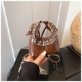 Dettaglio di una micro borsa in pelle marrone con volant a quadri e manici annodati chic - Marrone