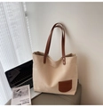 Close-up of minimalist canvas tote with brown leather pocket and refined stitch details - Beige Grey