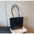 Minimalist black matte leather bucket bag shown on a book for a lifestyle aesthetic look - Black
