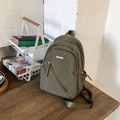 Bolso bandolera minimalista en nylon verde militar con etiqueta MACHUGE sobre madera - Verde