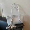 Large light blue leather tote bag with braided charm on stack of books - Blue (With Charm)