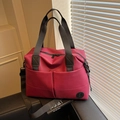Rose red high-capacity travel backpack with black straps shown on a leather sofa - Burgundy