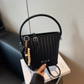 Black woven bucket bag with silver round handles and decorative wooden bead strap charm - Black