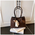 Detail of brown tote bag with woven texture, dual handles and cute plush dog charm - With Charm / Brown