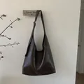 Detail einer dunkelbraunen Tasche aus Kunstleder mit verstellbarem Riemen und Schnalle - Braun