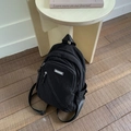 Minimalist black sling bag with diagonal zipper and MACHUGE logo on wooden floor - Black