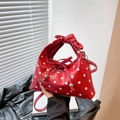 Red polka dot triangular handbag with bow handle and crossbody strap in a trendy urban style - Red