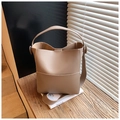 Beige bucket bag with contrast stitching on wooden surface with warm lighting - Khaki