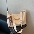 Chic off-white dumpling bag with pebble texture and T-tassel charm detail - Cream White With Pendant