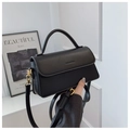 Detail of black leather shoulder bag showing gold metal hardware and matte finish texture - Black