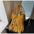 Detail of yellow fringe shoulder bag with long tassels and zip closure on black surface - Yellow
