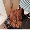 Detail of brown suede crossbody bag with long tassels and metallic zipper on a dark surface - Brown